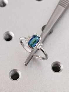 a diamond ring sitting on top of a table next to a pair of scissors and screwdrivers