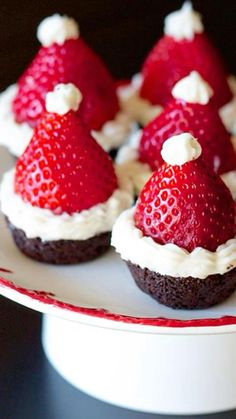 chocolate cupcakes decorated with strawberries and white frosting on a red plate