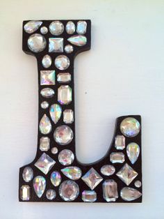 the letter j is made up of many small crystals and black metal pieces with white, iridescents