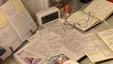 an assortment of books and papers on a table with a clock in the middle one