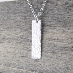 A modern take on a classic silver necklace. This necklace is specifically created to be just a whisper along your neck line, dainty, delicate, lightweight and beautiful. Perfect for layering with your favorite pieces. Elegant and dainty, this necklace consists of a vertical 1 inch Sterling Silver rectangle bar, hammered with my Classic texture and suspended from a dainty 1.9mm Sterling Silver cable chain. The pendant is suspended just over 1 inch in length from the chain. Bar Size: 1 Inch Neckla Huge Necklace, Minimalist Silver Necklace, Jewelry Layering Necklace, Minimalist Necklace Silver, Jewelry Layering, Silver Bar Earrings, Gold Lariat Necklace, Vertical Bar Necklace, Silver Bar Necklace