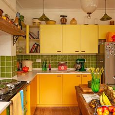 a kitchen with yellow cabinets and green tile backsplashing on the countertops