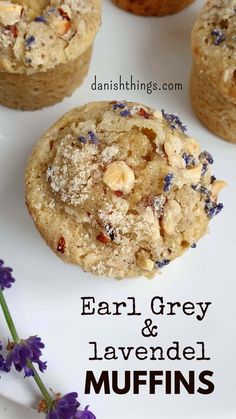 some muffins are sitting on a white plate with purple flowers in the background