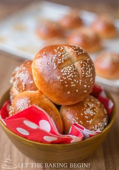 a bowl filled with sesame seed rolls on top of a wooden table