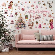 a pink couch sitting in front of a christmas tree and wall with stickers on it