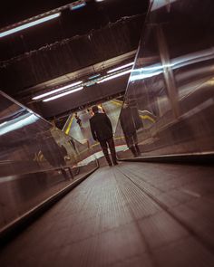 two people are walking down an escalator in a subway or subway car station