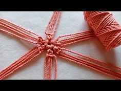 an orange string tied to a white cloth with two spools of thread on top