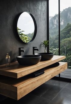 two black bowls sit on a wooden counter in front of a round mirror and window