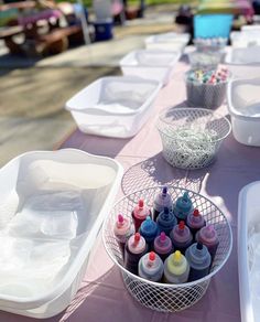 there are many cups and containers on the table with paint bottles in each one,