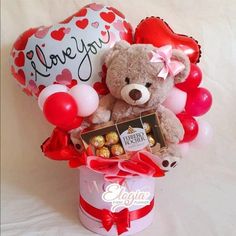 a teddy bear sitting in a bucket with balloons and heart - shaped balloons on it