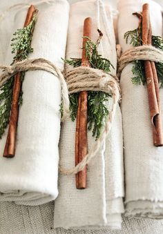 napkins wrapped in twine with cinnamon sticks tied to them and evergreen sprigs