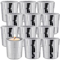 many silver cups with a lit candle in the middle and black squares on each side