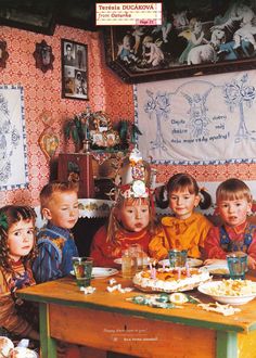 the children are sitting at the table with their birthday cake and candles in front of them