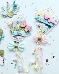 three different types of bows and tags on a white surface with confetti scattered around them