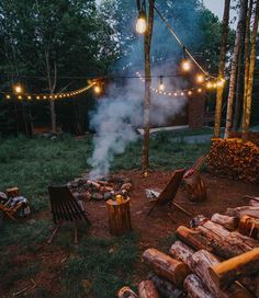 an outdoor fire pit surrounded by logs and string lights