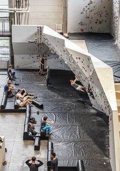 several people are climbing up and down the walls in an indoor climbing area with black tarps