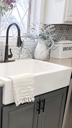 a kitchen sink sitting under a window next to a counter top with towels on it