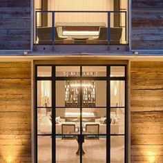 an open glass door leading to a living room and dining area in a house with wooden walls