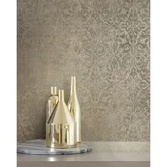 three bottles on a marble tray in front of a wallpapered background with an intricate design