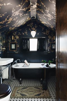 a bathroom with black and gold wallpaper on the walls, a claw foot bathtub in the middle