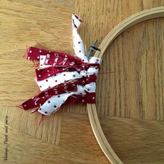 a red and white bow sitting on top of a wooden table next to a hoop