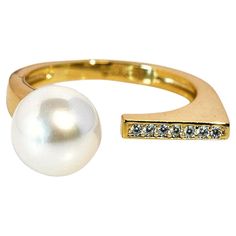 An open ring, plated in 14k gold over sterling silver, boasts a singular white freshwater pearl on one end and a radiant line of diamonds on the other. This design symbolizes the intertwining of two souls, with the pearl embodying purity and the diamonds reflecting everlasting commitment—a testament to enduring love in its simplest, most elegant form. Specifications: - Metal Type: Sterling Silver - Diamonds: Cubic Zirconia - Ring Weight: 3 Grams - Pearl Type: Freshwater Pearl - Pearl Size: 8.5 mm - Pearl Shape: White - Pearl Shade: Round - Pearl Surface: Clean - Pearl Shine: AAA – Excellent - Ring Size adjustable: Yes - Ring Size: Indian size 10 to 20, US size 5 to 9.25 Elevate your style and make a statement with our Designer Open Ring. Discover the perfect blend of classic elegance and c Modern 14k Gold Pearl Open Ring, Cubic Zirconia Rings, White Freshwater Pearl, Minimalist Ring, Pearl Types, The Pearl, Minimalist Rings, Open Ring, Pearl Size