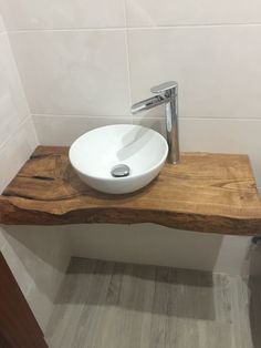 a white bowl sink sitting on top of a wooden counter