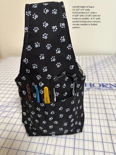 a black and white dog paw print backpack with three zippers on the front pocket