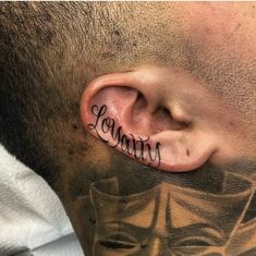 a man with tattoos on his neck and behind the ear that reads lovinin