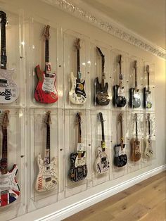 the wall is filled with many guitars on display in clear acrylic cases,