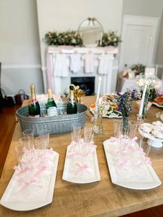 three wine glasses are sitting on plates with pink bows and champagne bottles in the background