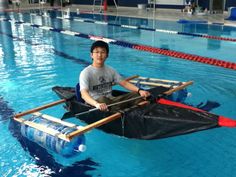 a man sitting on top of a boat in a swimming pool with two oars