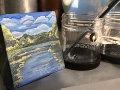 an acrylic painting is sitting on a table next to some jars