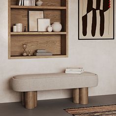 a white bench sitting in front of a wooden shelf filled with books and vases