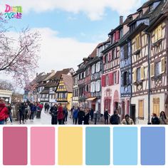 people are walking down the street in front of old buildings with colorful paint swatches