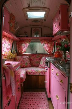 the interior of a pink camper van with floral curtains and rugs on the floor