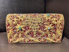 Beautiful hand-embroidered floral silk clutch bag inlaid with semi-precious stones. The front is completely covered in the design and has a closure flap with magnettic snap fastening. This clutch is perfect for daytime or night time. It is the ideal size for fitting all your essentials. It is a stylish accessory for each & every occasion. This equisite piece is even ideal for gifting to your near & dear one's . Thread - Silk Fabric - Velvet Variety of Semi-precious stones are used in this piece Zardozi is a type of heavy and elaborate metal embroidery on silk, satin, or velvet fabric base. Designs are often created using gold and silver wires and can incorporate pearls, beads, and precious stones. The embroidered silk clutch bag is made in Agra, India & is fully handmade. Designed to compl Traditional Embellished Clutch For Festivals, Traditional Embellished Evening Bag For Festivals, Traditional Embellished Evening Bag For Festive Occasions, Rectangular Clutch With Gold Embroidery For Festivals, Rectangular Gold Embroidered Clutch For Festivals, Rectangular Gold Embroidery Clutch For Festivals, Festive Multicolor Embroidered Handwork Clutch, Traditional Multicolor Embroidered Clutch For Evening, Formal Clutch With Intricate Embroidery For Festivals