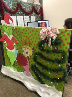 an office cubicle decorated for christmas with the grin's tree and presents on it