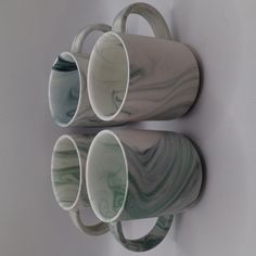 three marbled coffee mugs are hanging on the wall next to each other with handles