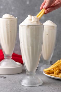 two glasses filled with whipped cream and french fries on a table next to each other