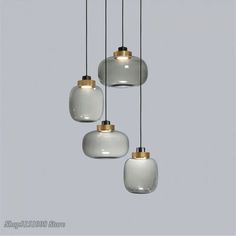 three white and gold glass pendants hanging from a ceiling fixture in a room with gray walls