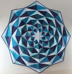 a blue and white circular quilt hanging on the side of a wall in a room