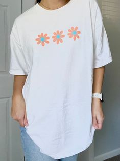 "White t-shirt with 3 peach & blue daisies. Adorable tee for summer! Color: Comfort Colors \"white\" ✰ MODEL INFO: ✰ Height: 5'4\" Size: normally wears a small, but is modeling a large for an oversized look. ★ MATERIAL: ★ 100% cotton" White Tshirt, Graphic Tees Women, White T, Comfort Colors, Womens Clothing Tops, Daisy, T Shirts For Women, Mens Graphic Tshirt, Tops & Tees