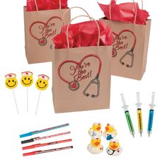 two brown bags with red ribbon and embellishments on them next to pens and markers