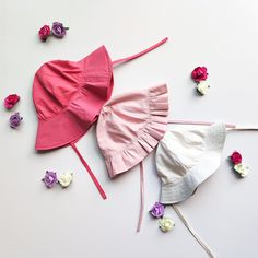 two pink and white bonnets with flowers around them