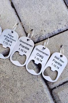 four keychains with names on them are sitting on the ground in front of a brick