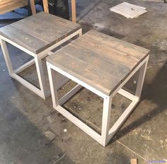 two wooden tables sitting next to each other on top of a cement floor in a warehouse