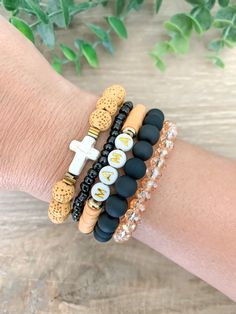 "Look at this beautiful black and mustard/gold bracelet stack. It has 5 bracelets that you can purchase as one or purchase separately. The first bracelet is 8mm mustard yellow lava stone diffuser beads and gold accents and a cream cross. The second bracelet is / black seed beaded bracelet. The third bracelet is a black and mustard/gold heishi beaded bracelet with MAMA beads. The fourth bracelet is a matte black beaded bracelet. The fifth bracelet is a gold rondelle glass beaded bracelet. As for Mothers Day Bracelets Diy, Cross Beaded Bracelet, Gold Bracelet Stack, Stackable Beaded Bracelets, Black Beaded Bracelet, Gold Bracelets Stacked, Stone Diffuser, Clay Bracelets, Mama Bracelet