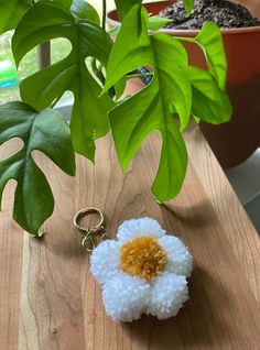 a keychain with a flower on it sitting next to a potted plant