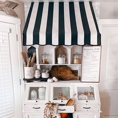 an old fashioned kitchen with white cabinets and black and white striped awning